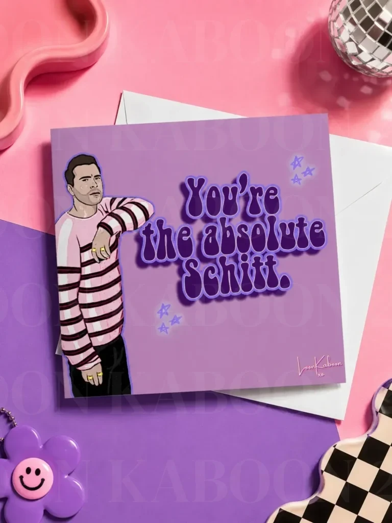 Schitt's Creek "Simply The Best" Greeting Card flat lay on colourful table.