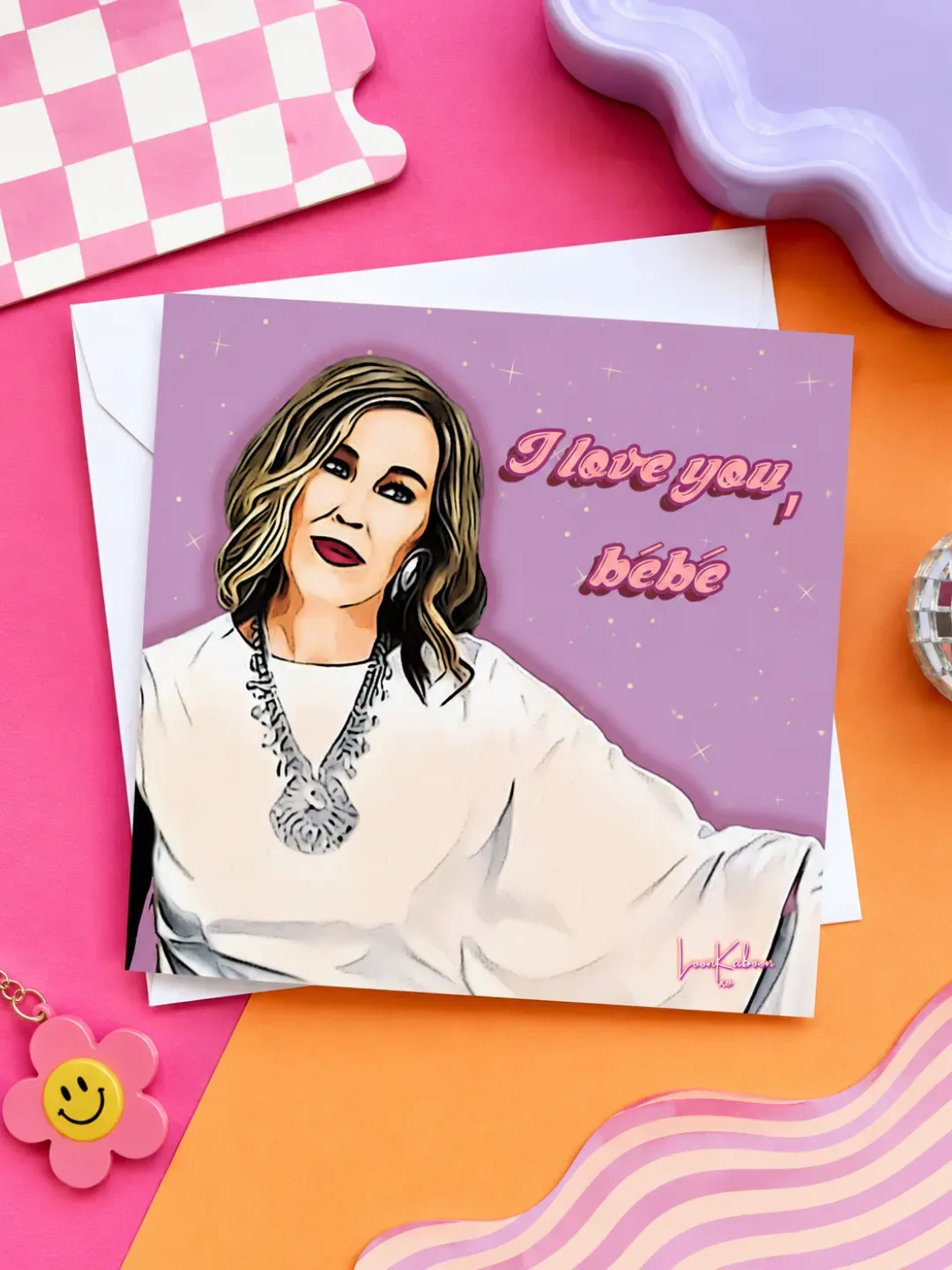 Moira Rose 'i Love You Bébé' Greeting Card flat lay on colourful table.