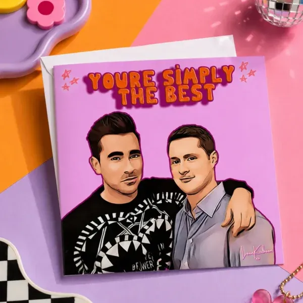 Schitt's Creek "Simply The Best" Greeting Card flat lay on funky colourful table.