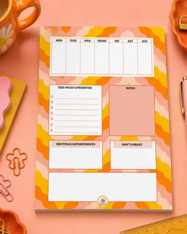 Weekly Planner A5 Notepad on a funky desk with pens, paperclips and other desk items.