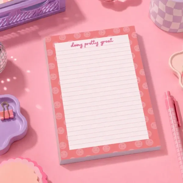 Doing Pretty Great A5 Notepad on a funky desk with pens, paperclips and other desk items.