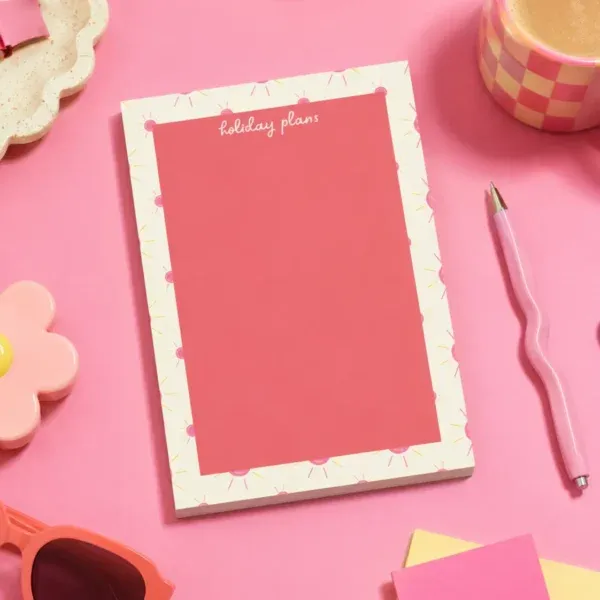 Holiday Plans A5 Notepad on a funky desk with pens, paperclips and other desk items.