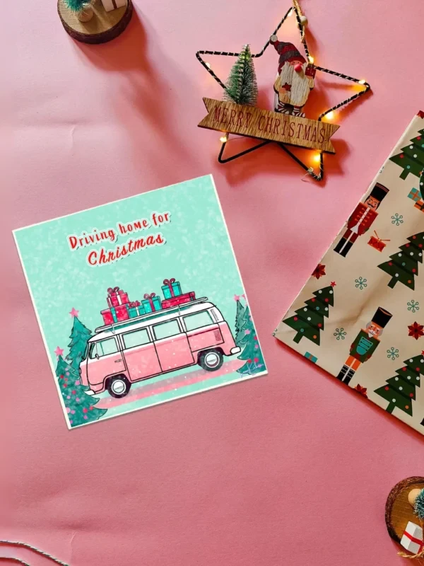 Driving Home for Christmas Flatlay Driving Home for Christmas card with a pink campervan illustration by Loon Kaboon